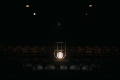 A light on the stage in the dark with theatre seats behind them